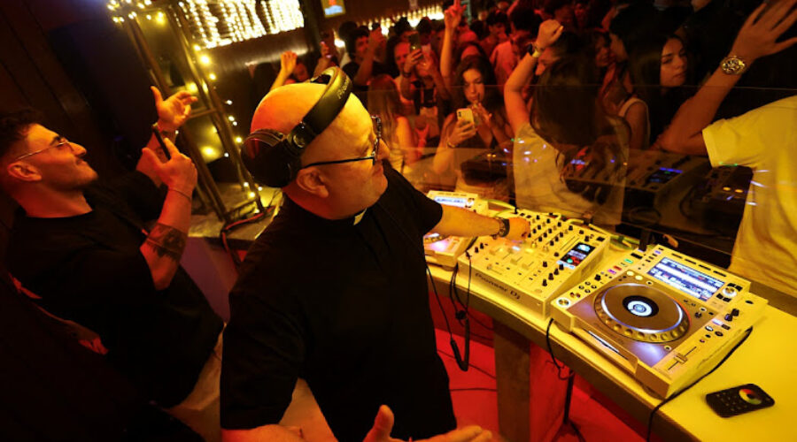 DJ priest Guilherme, wearing a rosery, plays music in the parish bar of Laundos, Povoa do Varzim